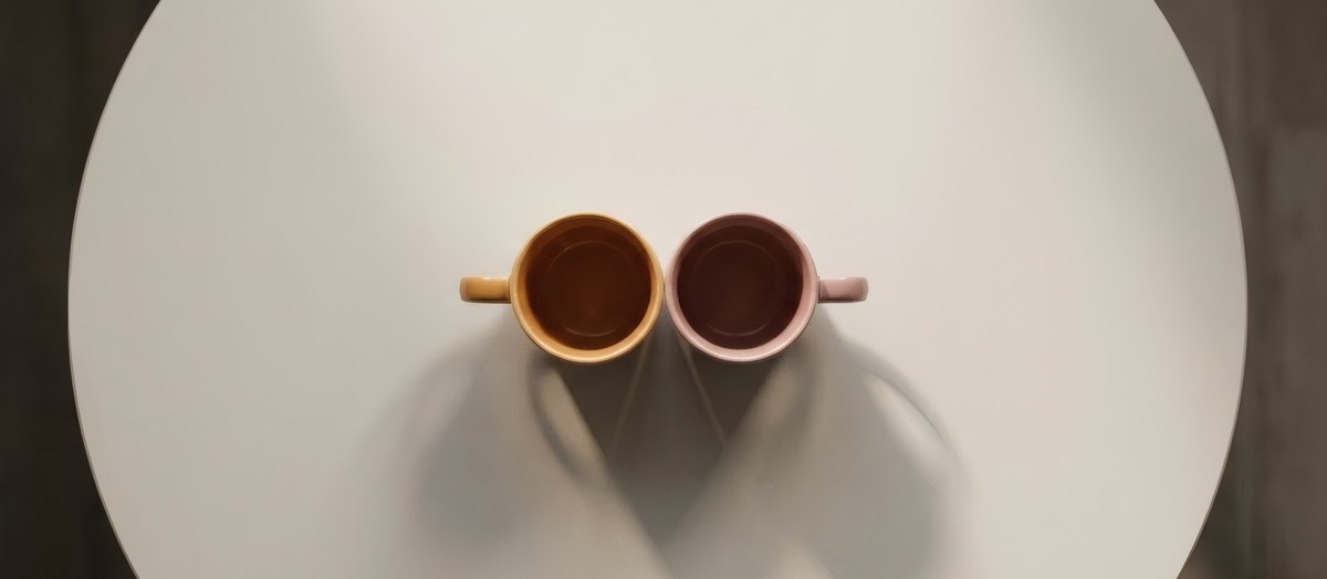Twee kopjes dicht bij elkaar op een cafétafel, van bovenaf gezien, bij vijftig jaar relatieonderzoek